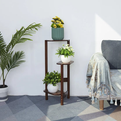 Dark brown bamboo corner plant stand with three tiers rounded edges angled legs holding various potted plants