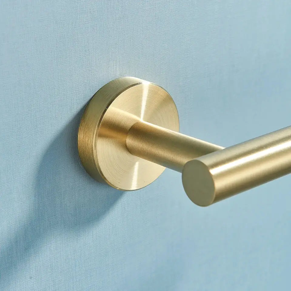 Brass-finished wall-mounted towel rack with sleek cylindrical bar and circular base in decorbites bathroom hardware set
