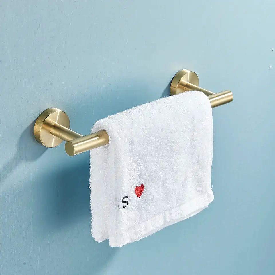 Gold-toned double towel rack holding a white embroidered hand towel from decorbites bathroom hardware set