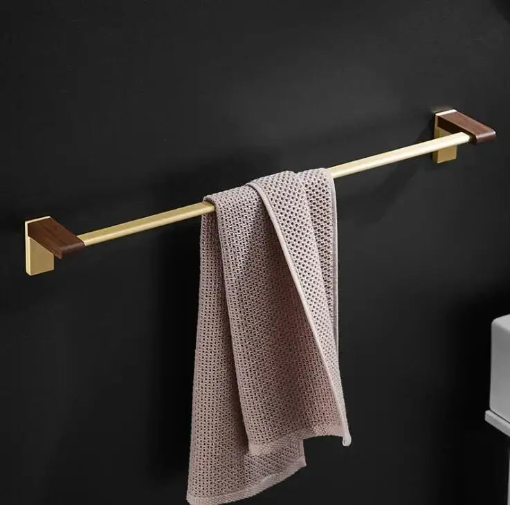 Gold-toned towel rack with dark wood end caps holding beige mesh towel from DecorBites™ bathroom hardware set in space aluminum