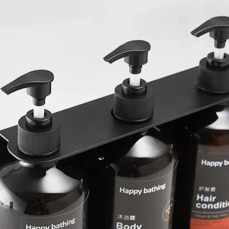 Black metal liquid soap dispenser rack holding three dark glass bottles with black pumps made of sus 304 and abs materials