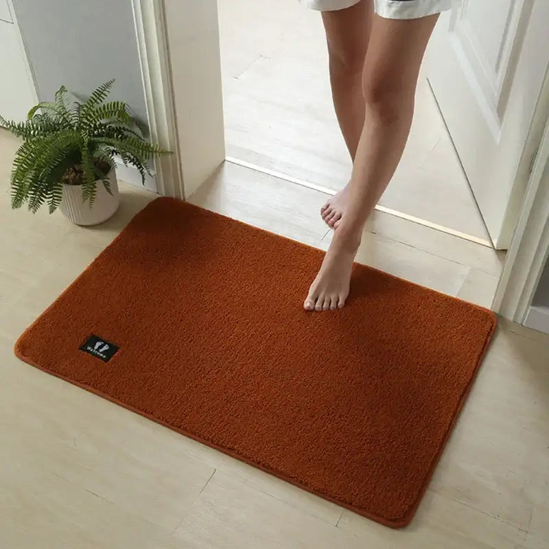 A rust-orange decorbites bathroom mat with soft textured surface, non-slip, absorbent, and quick drying features