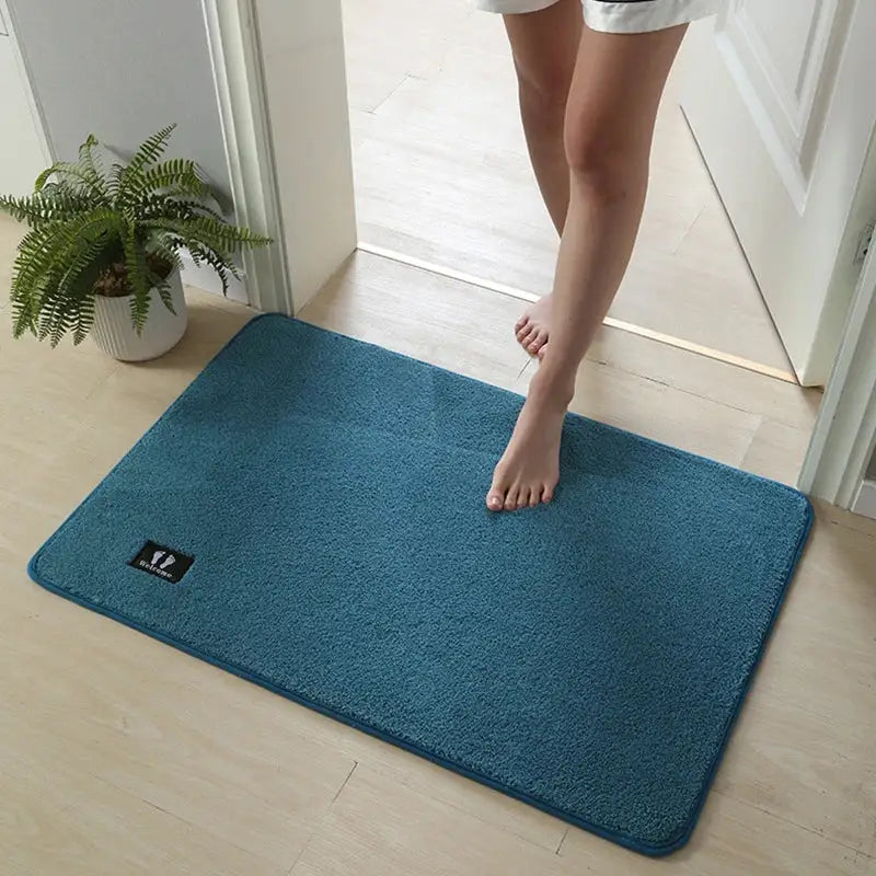 Teal rectangular decorbites bathroom mat with plush textured surface and small black logo patch in corner