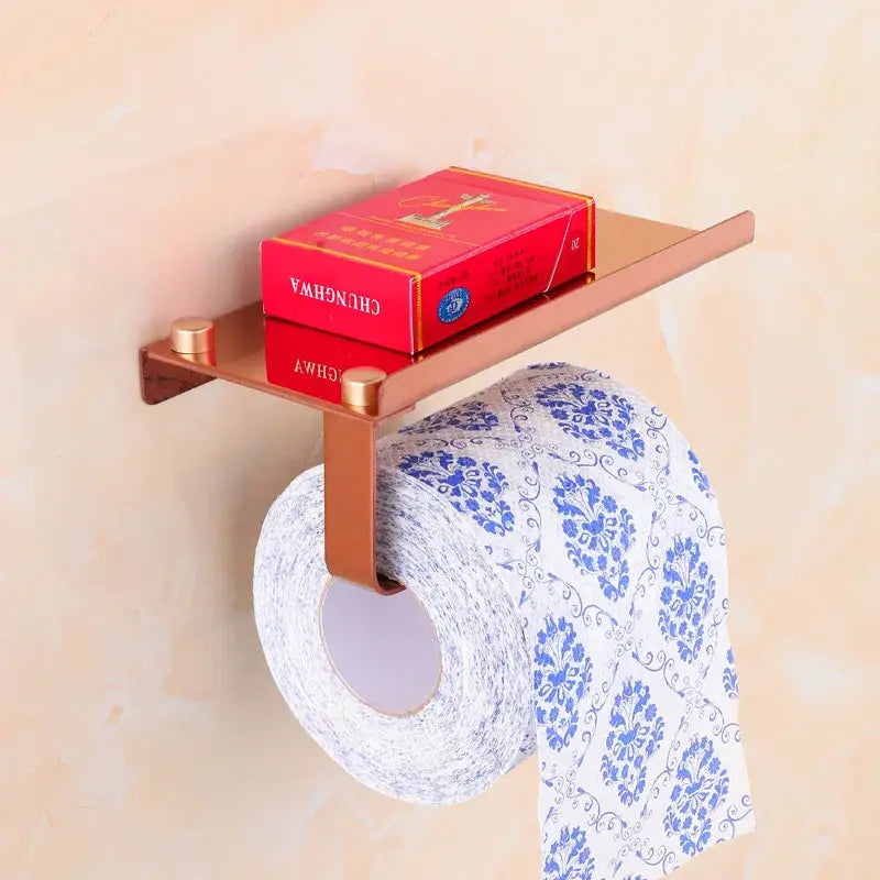 Rose gold decorbites bathroom paper holder with integrated shelf holding red cigarette pack for bathroom paper phone use
