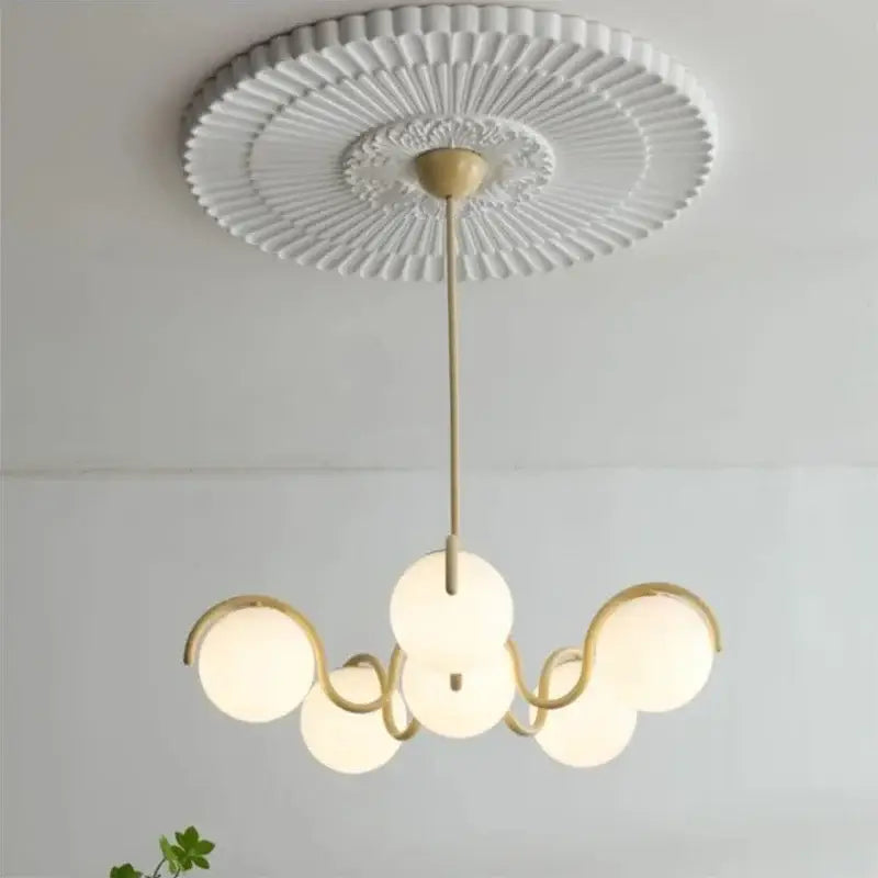 A decorbites bean glass pendant light with gold metal frame and frosted globes hanging from a white ceiling medallion