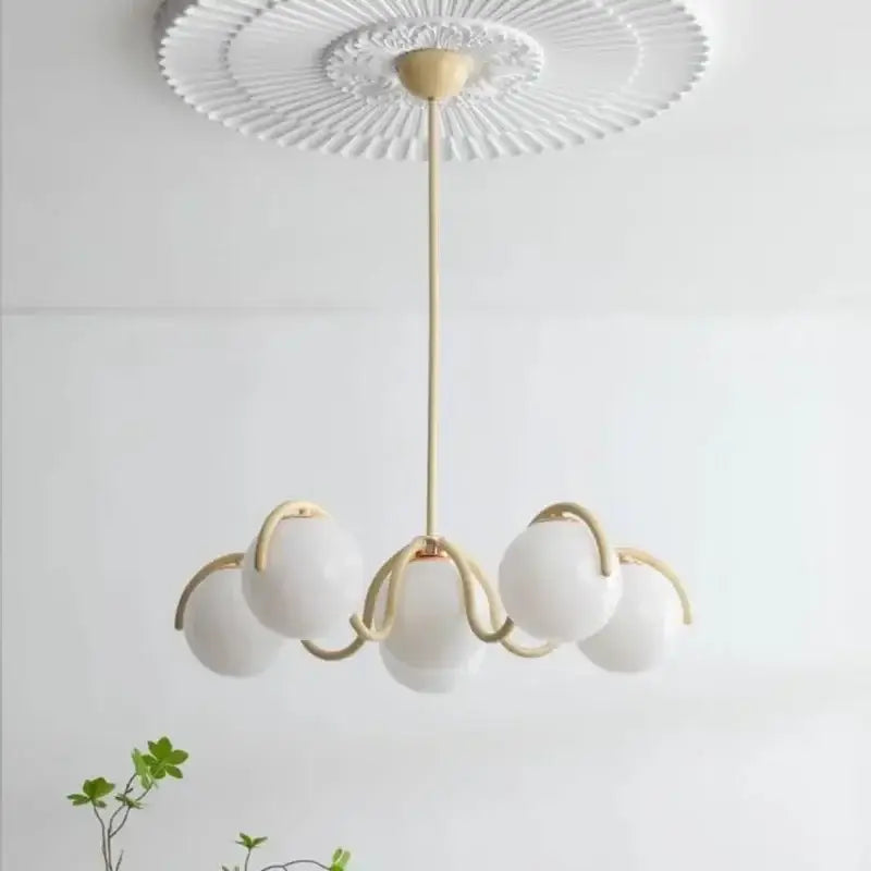 A decorbites bean glass pendant light with five frosted glass globes and gold-toned arms in red and cream for living spaces
