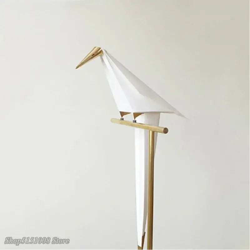 Decorbites bird origami floor lamp features a minimalist white origami bird with gold beak and feet on a wooden stand
