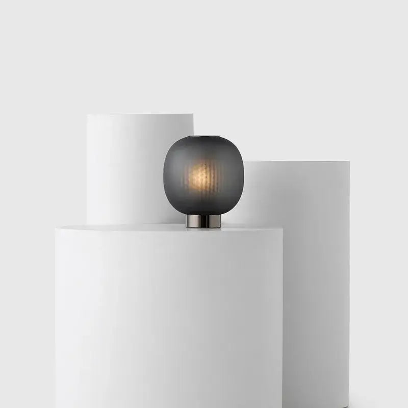 A sleek table light with a dark gray frosted black glass ball shade and metallic base by DecorBites black glass