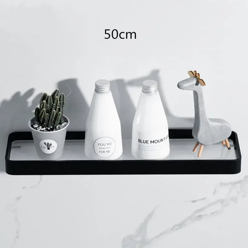 Black glass decorbites bathroom shelf corner rack with glossy finish holding white bottles and a small potted cactus