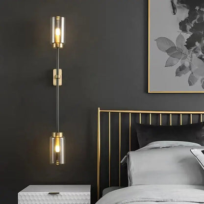 Gold-toned wall lamp with two cylindrical glass shades and a black stem from decorbites black glass wall collection