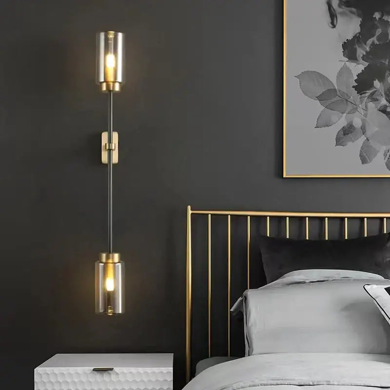 Gold-toned wall lamp with two cylindrical glass shades and a black stem from decorbites black glass wall collection