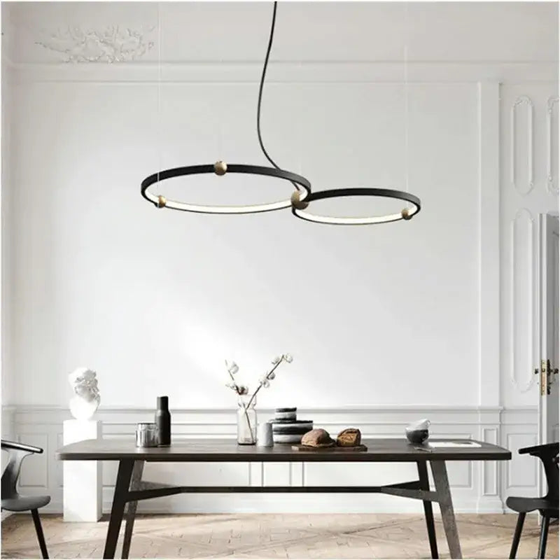 Modern black gold chandelier with metal LED rings hanging above a dining table by DecorBites black gold