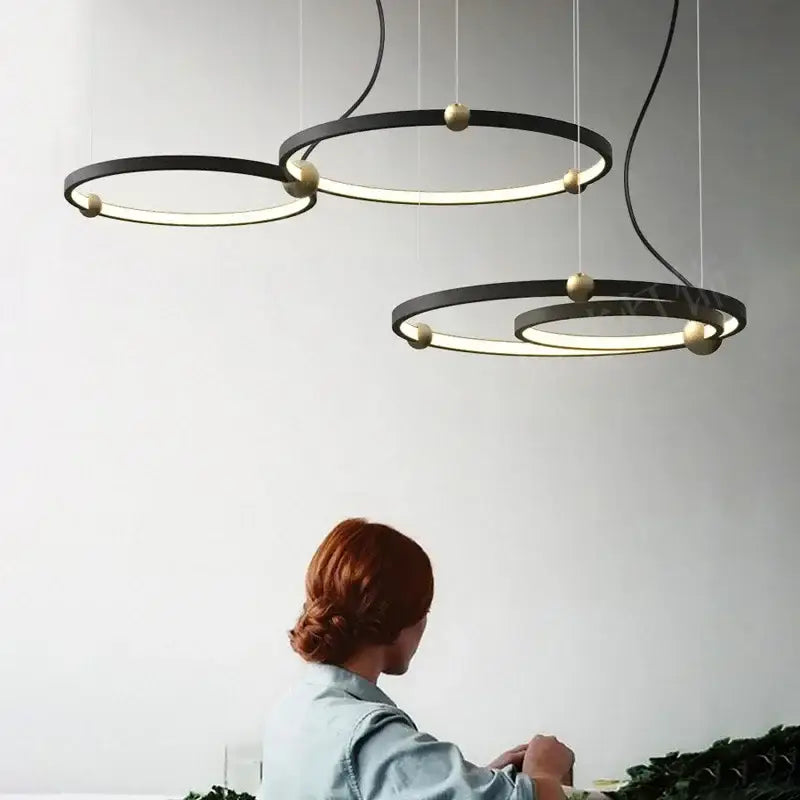 DecorBites black gold chandelier with modern black circular metal LED rings and gold-toned spherical accents