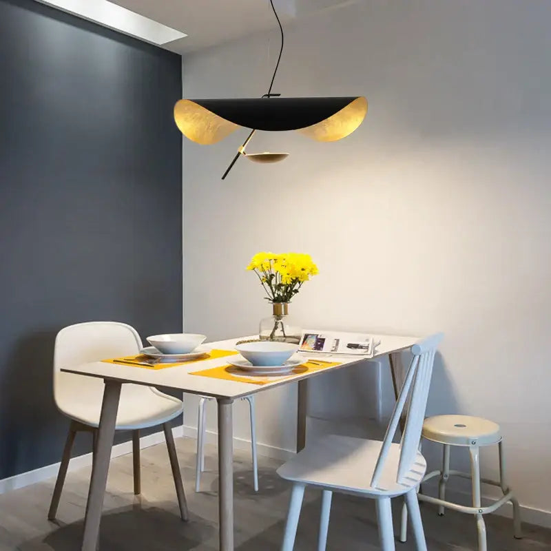 Modern black gold DecorBites pendant light with sleek curved glass ball design hanging above dining table