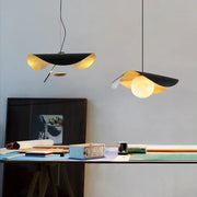 Two decorbites black gold pendant lights with leaf-like glass shades hang above a desk in retro Nordic style