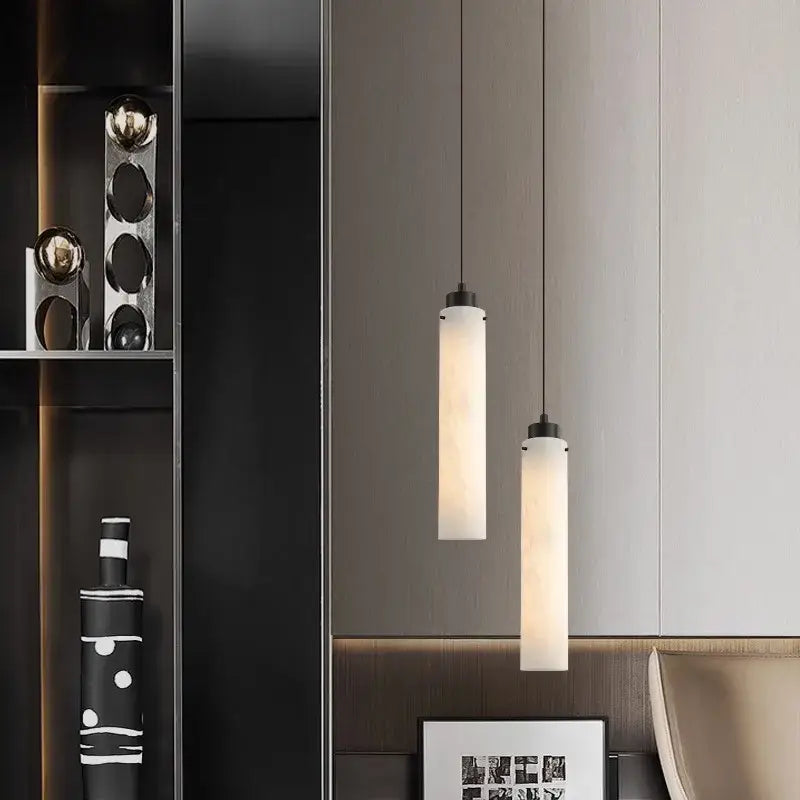 Two minimalist decorbites black gold marble pendant lights with frosted glass shades and black metal fixtures hang from ceiling