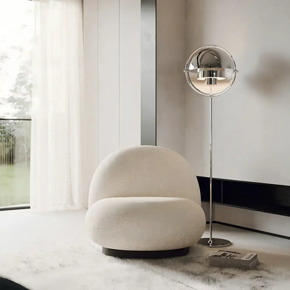Cream-colored plush spherical armchair with black circular base paired with decorbites black gold metal floor lamp for modern décor