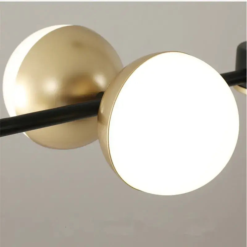Modern pendant light with two gold spherical fixtures and black rod in decorbites black gold minimalist chandelier design