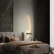 DecorBites black gold modern wall sconce with a crescent-shaped metallic frame and warm ambient indoor lighting