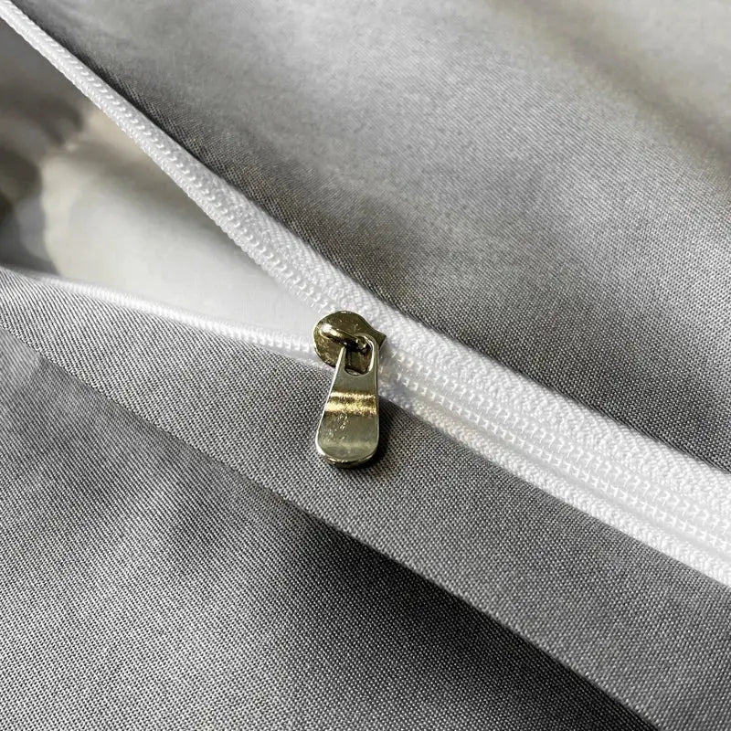 A metallic gold zipper pull on a white zipper track of the DecorBites black grey marble ice silk duvet cover set