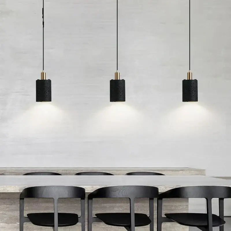 Three black cylindrical pendant lights with textured surfaces and gold accents from decorbites black hole stone chandelier