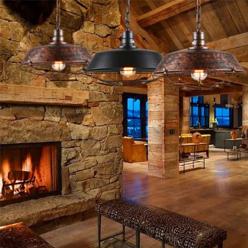 Three rustic decorbites black industrial pendant lights with weathered metal shades hang above a stone fireplace