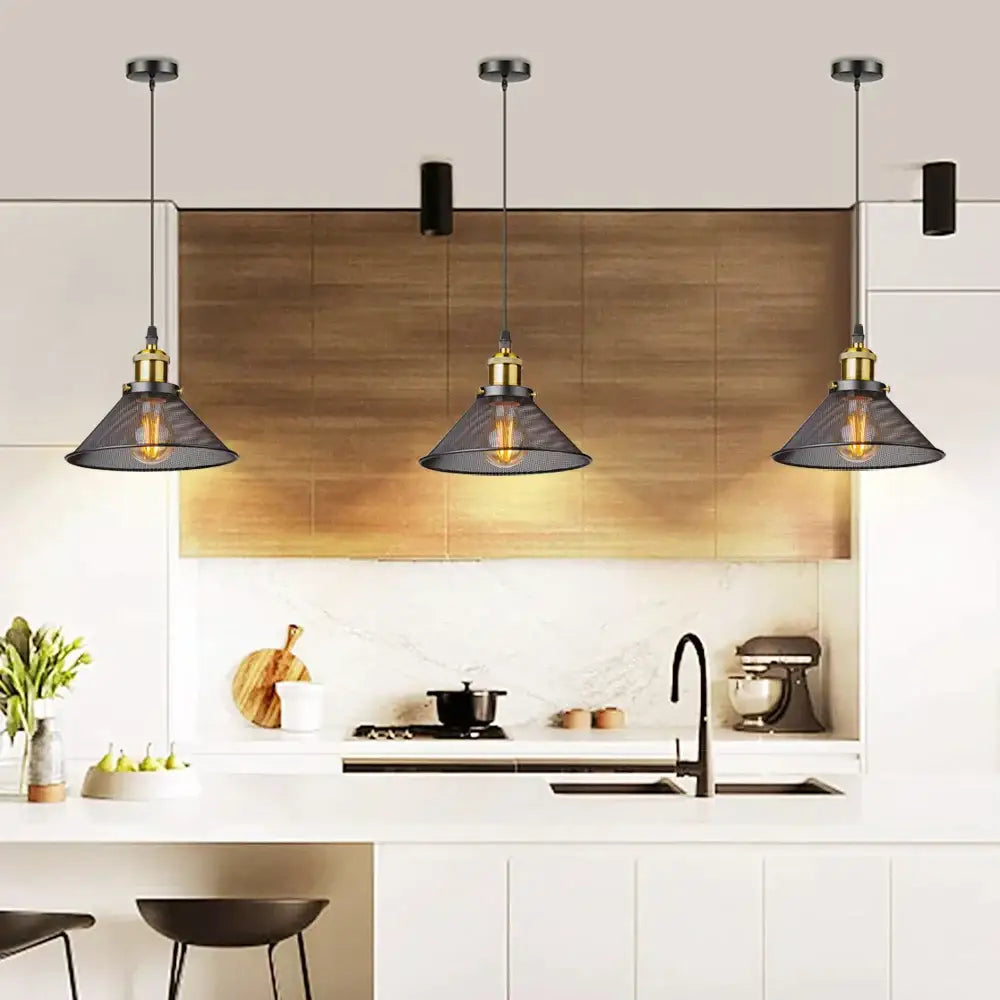 Three black iron cage pendant lights with dark gray mesh shades and brass accents hang above a kitchen island
