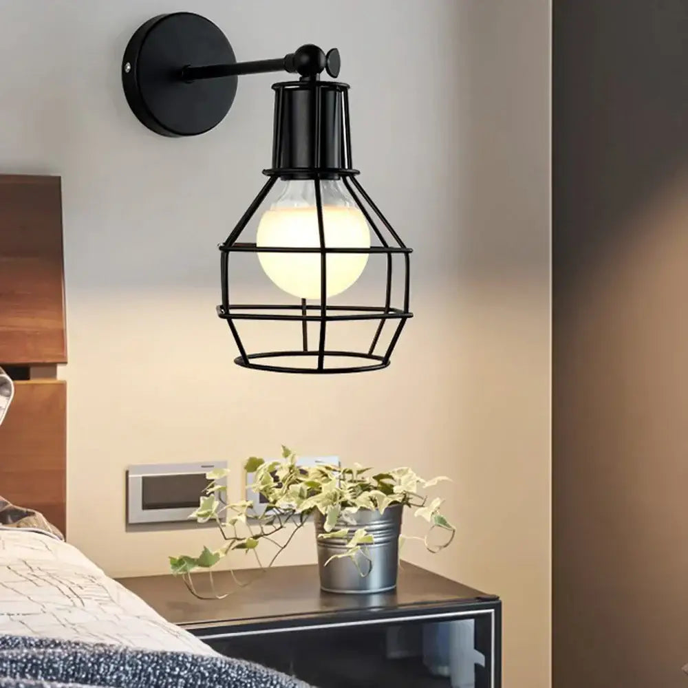 Black wrought iron wall lamp with iron cage design and exposed bulb by DecorBites black iron for indoor use