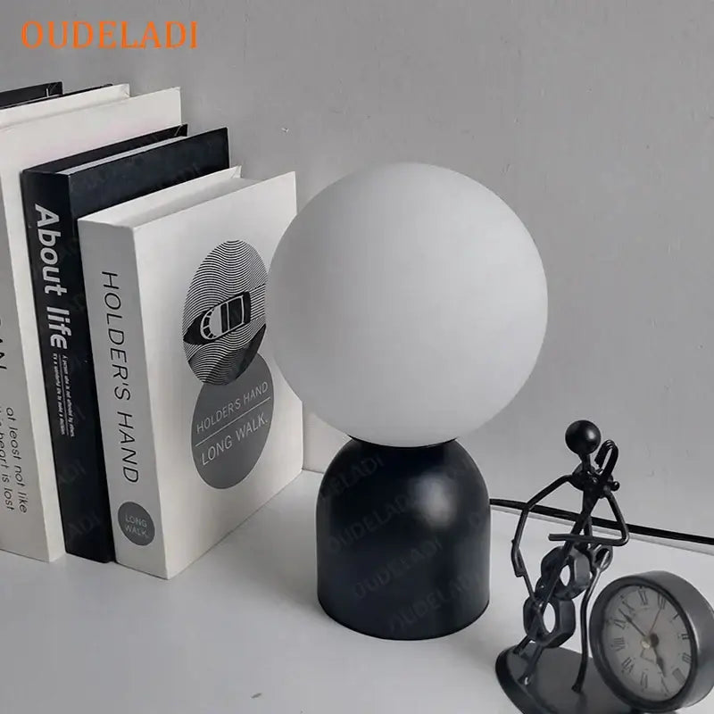 A sleek black iron decorbites black iron table lamp with a frosted glass globe on a matte black base for home decor