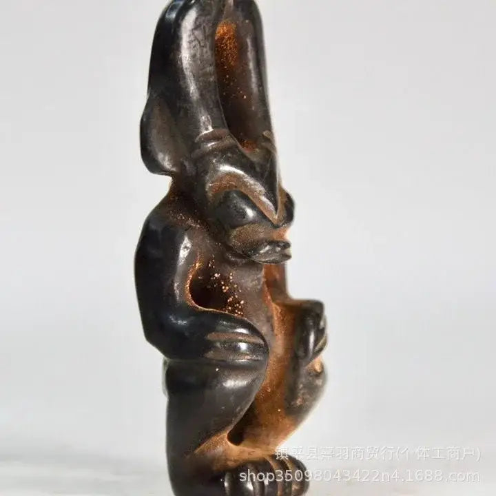 Dark polished jade carving of a stylized rabbit with golden inclusions in decorbites black iron meteorite sun statue