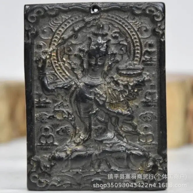 Dark metallic rectangular pendant with intricately carved deity and circular halo from decorbites black iron meteorite sun collection