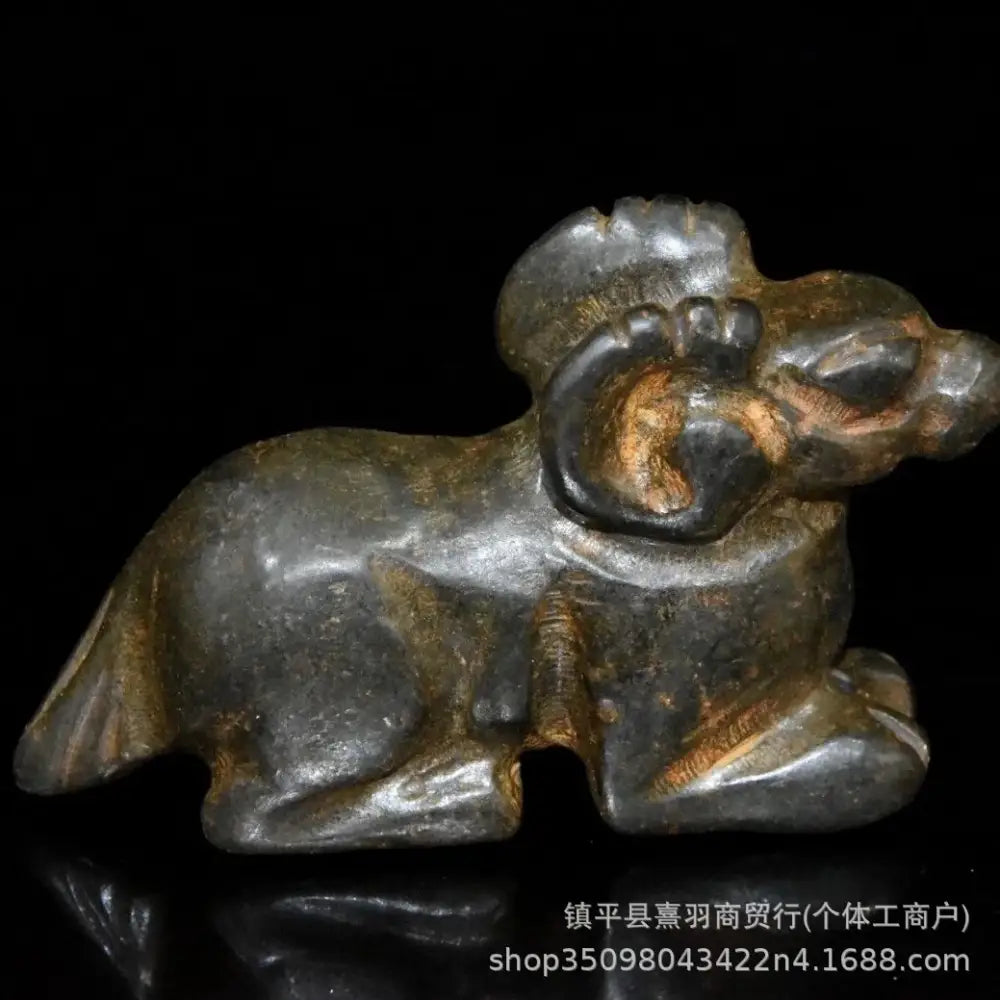 Dark gray stone carving of a reclining ram with copper patina accents in decorbites black iron meteorite sun god statue