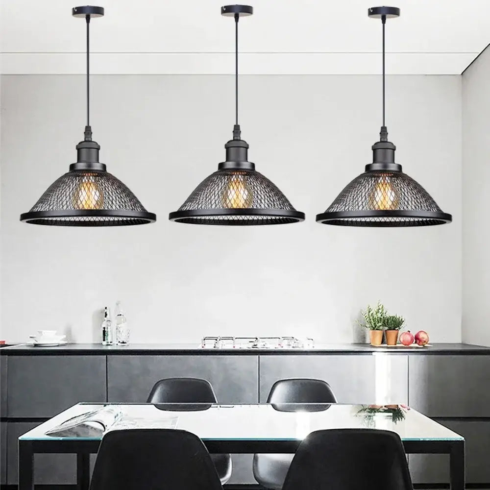 Three black iron decorbites pendant lights with mesh net-cage shades hang above a dining table for kitchen use
