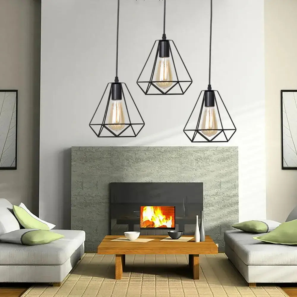 Three black iron pendant lights with exposed filament bulbs hang above a modern fireplace by DecorBites