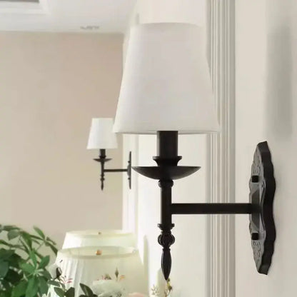 Decorbites black iron wall lamp with black wrought iron frame and white fabric shade for bedroom and living room decor