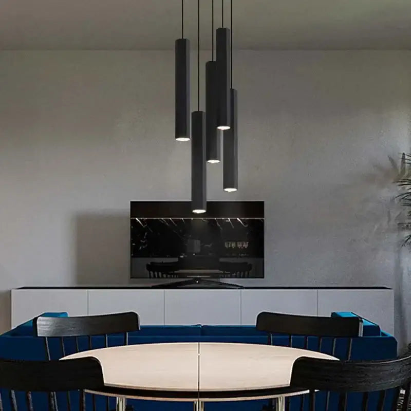 Modern nordic decorbites black led crystal cylindrical pendant lights hang clustered above a dining table