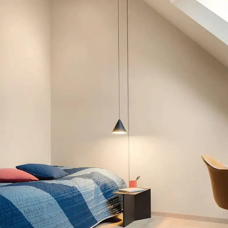 A sleek black conical decorbites black led pendant chandelier hanging over a bedside table for modern bedroom decor