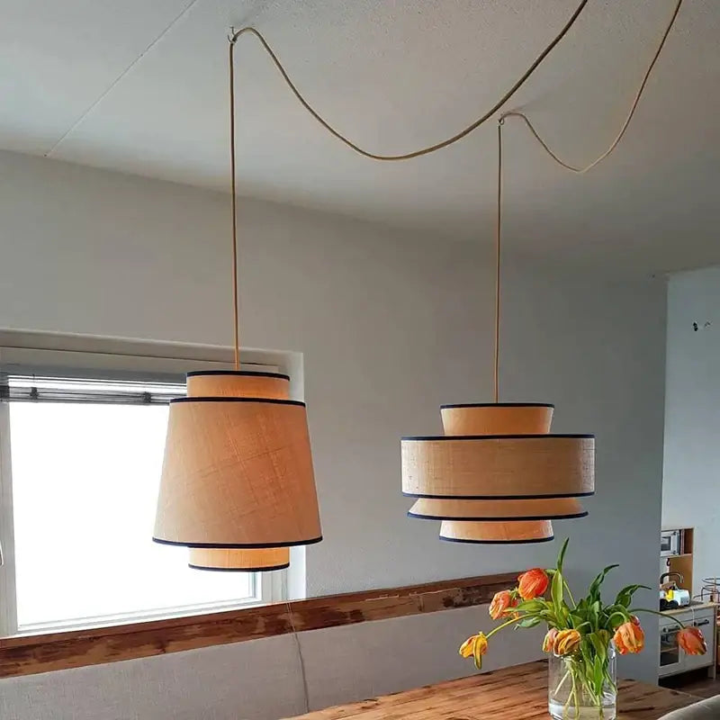 Two beige tiered pendant lights with black trim featuring black led strip illumination for dining and living rooms