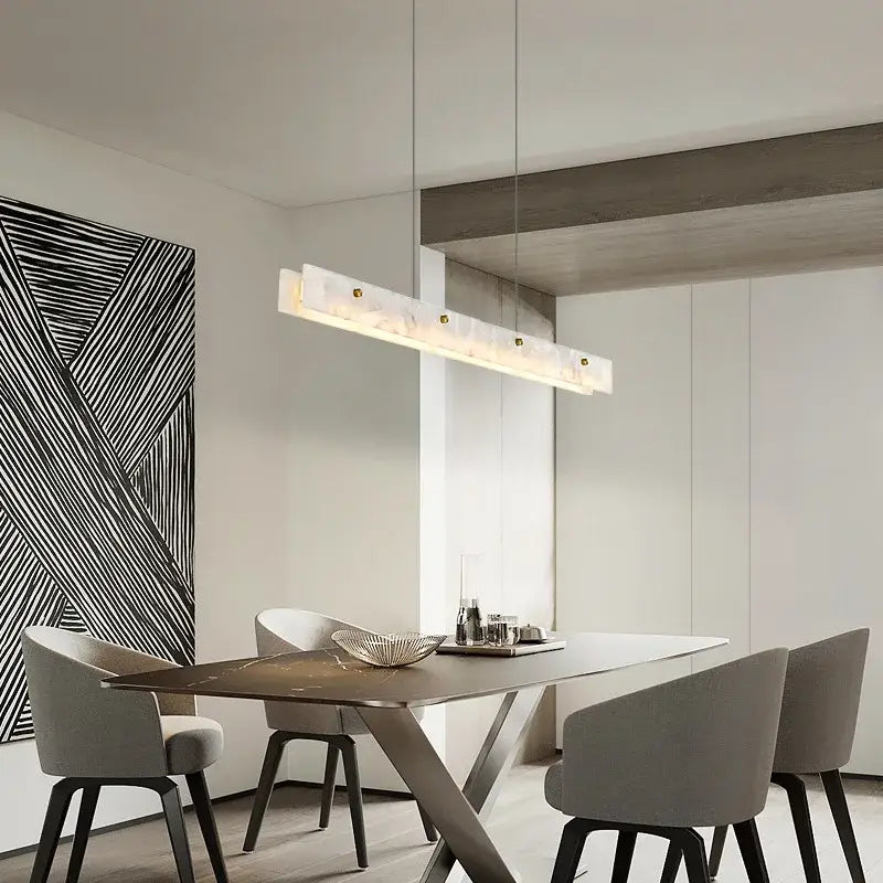 A decorbites black marble pendant chandelier with white marble finish and gold accents hangs above a dining table