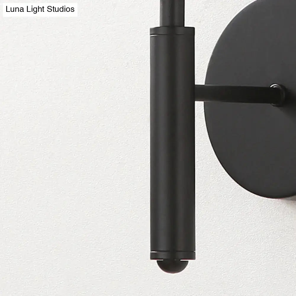 Modern black wall sconce with clear textured glass features a black matte cylindrical stem and circular backplate for bedroom lighting