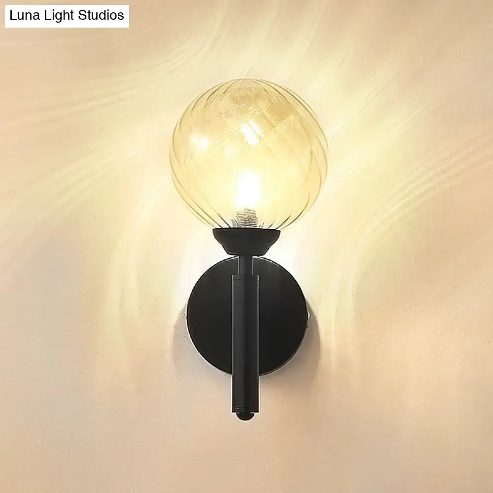 Modern black metal wall sconce with amber clear textured glass globe for bedroom lighting