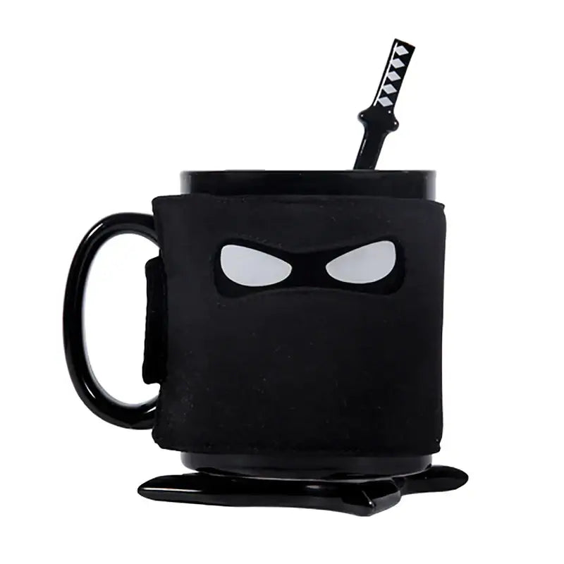 Decorbites black ninja mug with matte finish white eye cutouts and matching black sword stirrer kitchen novelty cup
