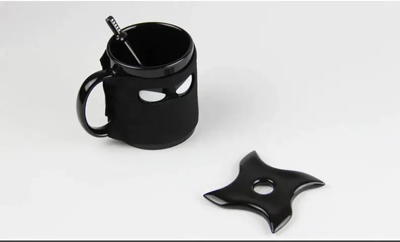 A decorbites black ninja mug with eye cutouts and matching black shuriken spoon plus a separate star-shaped throwing star