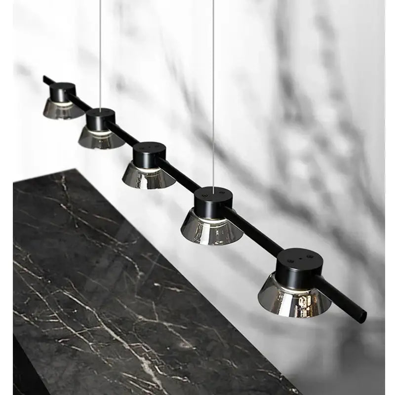Modern decorbites black strip chandelier featuring five sleek black and chrome cylindrical bulbs suspended by thin cords