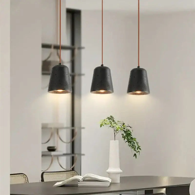 Three black travertine led pendant lamps with warm glow hanging from copper cords by decorbites for dining room