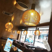 Warm-toned woven bamboo pendant light with spherical design and vertical slats for decorbites black wood cage chandelier