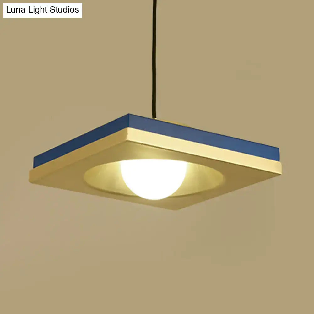 Modern blue and cream-colored pendant light with metal concave squares and warm glowing bulb base for bedrooms by DecorBites