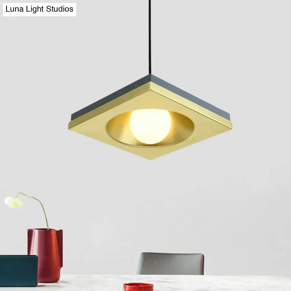 DecorBites™ blue and gold pendant light with square brass frame, dark gray bulb base, and illuminated circular bulb for bedrooms