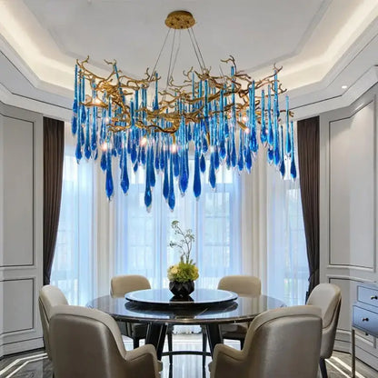 Decorbites blue crystal chandelier with striking blue glass and gold branching arms hanging above dining table