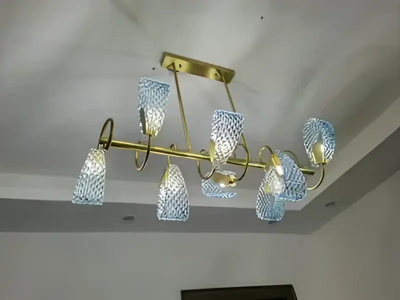A modern chandelier with a brass frame featuring multiple blue glass led pendant lamps for designer lighting